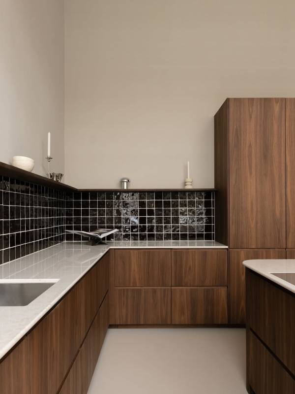 Keuken met glanzende Azulejos Chocolate, lichte voegen, houtkleurige fronten en een licht werkblad.
