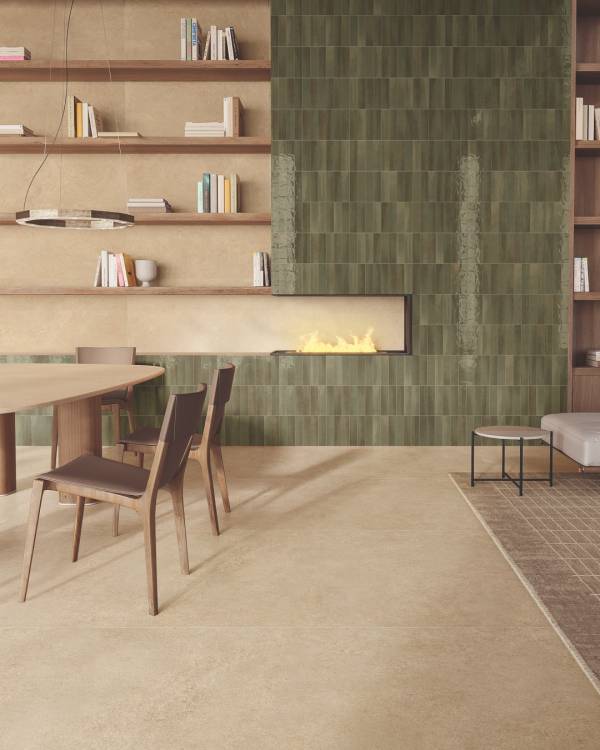 Haardwand met glanzende olijfgroene tegels, houten meubels en open planken boven een zandkleurige vloer.