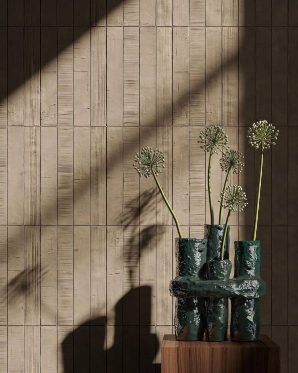 Beige Kore-wandtegels met afwisselend reliëf, naast een donkergroene vaas met bloemstelen op een houten sokkel.