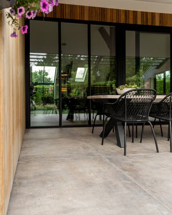 Grootformaat terrastegels in grijsbruine tinten op een overdekt terras bij Van der Rijt Tegels Uden