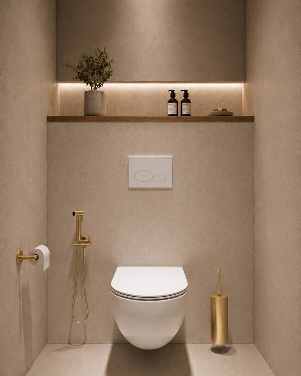 Bidetset met handdouche in messingkleur naast een wit wandcloset in een beige toiletopstelling bij Wiesbaden