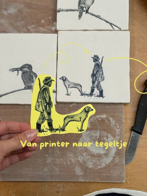 Bedrukte keramische tegels met vogels en een jager met hond op de werktafel bij De Steenen Vloer in Halle